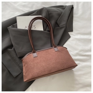 Détail d'un sac à main en daim marron avec des poignées en cuir sur une veste grise