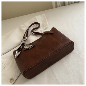 Détail du grand sac cabas en cuir marron foncé avec accessoire élégant en foulard de soie