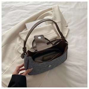 Detail showing grey tweed handbag with brown leather trim on a white blazer