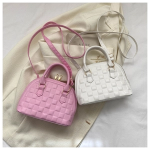 Close-up of pink and white shell-shaped handbags with textured lattice pattern and gold zipper