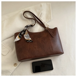 Détail macro du sac cabas en cuir marron avec surpiqûres blanches et foulard en soie