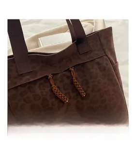Macro view of leopard print tote bag with brown woven zipper details and fabric texture