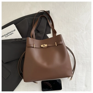 Dettaglio della borsa tote marrone scuro con chiusura a rotazione dorata e pelle opaca