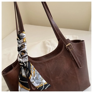 Détail du cabas en cuir marron foncé avec surpiqûres blanches et foulard en soie