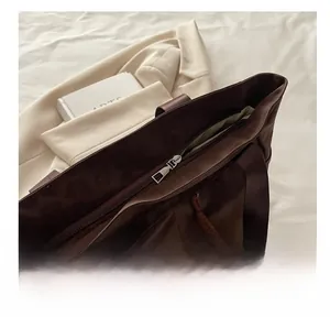 Detail shot of smooth zipper closure and fabric handles on a brown tote bag