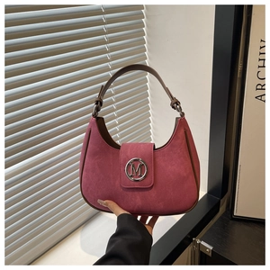 Detail of rose pink suede hobo bag with brown leather strap and silver M letter metal buckle