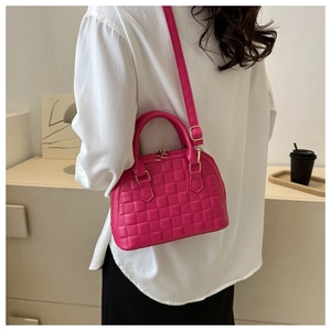 Close-up of bright pink shell bag with square embossed texture and gold hardware