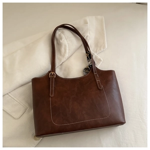 Close-up of brown faux leather tote bag with contrast stitching and decorative scarf