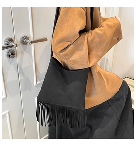 Détail du sac noir à franges en daim avec bandoulière porté par un mannequin