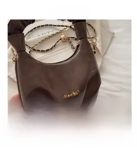 Close-up of pleated dark brown leather cloud bag with gold chain and logo detail