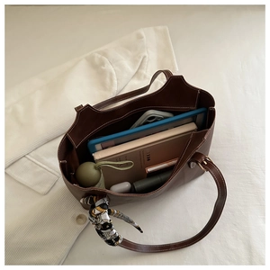Top view of spacious brown tote bag interior holding tablet, notebook and daily items