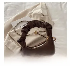 Detail of soft dark brown leather ruched handle and golden chain on cloud bag