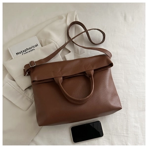 Close-up of brown litchi textured leather tote bag with adjustable long shoulder strap