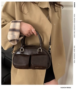 Detail of dark brown leather handbag with double front pockets and adjustable gold-tone strap