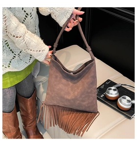 Détail du sac cabas en daim marron avec de longues franges bohèmes et une bandoulière en cuir