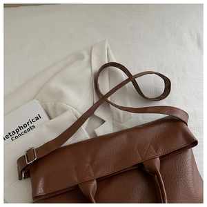 Detailed close-up of brown litchi pattern tote bag with adjustable strap on white fabric