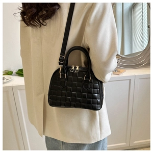 Detail of black quilted shell bag with gold zippers and detachable shoulder strap