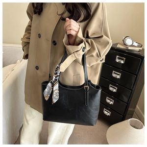 Détail du sac cabas en similicuir noir avec foulard en soie vintage sur la poignée