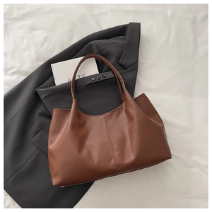 Minimalist brown faux leather large tote bag on a textured white fabric and grey suit