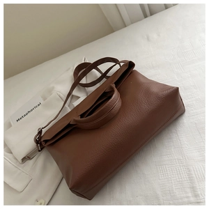 Detail of brown litchi pattern leather tote bag with silver metal hardware and double handles