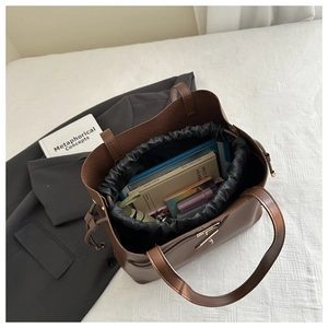 Vista dall'alto di una borsa a secchiello in pelle marrone con spazio per tablet e libri