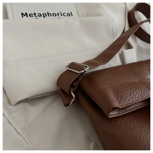 Detail of deep brown pebble texture leather flap bag with silver metallic hardware buckle