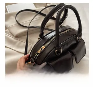 Detail of dark brown leather Boston bag showing dual front pockets and smooth gold zippers