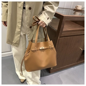 Dettaglio della chiusura a girello dorata e cinturini decorativi su borsa a secchiello