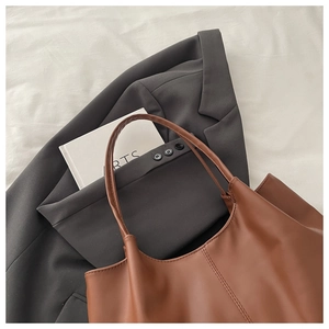 Flat lay of brown leather tote bag showing fine stitching and polished texture