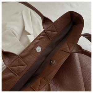 Detailed close-up of dark brown tote bag with magnetic clasp and pebble grain texture