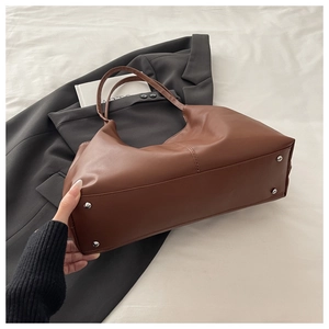 Detail of a brown PU leather tote bag base featuring four protective metal rivets