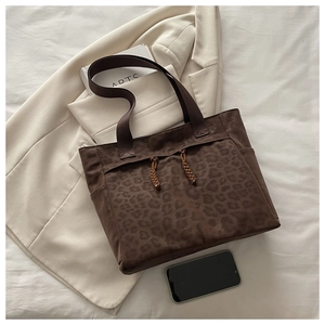 Close-up of leopard print tote bag with woven drawstring details and wide fabric handles