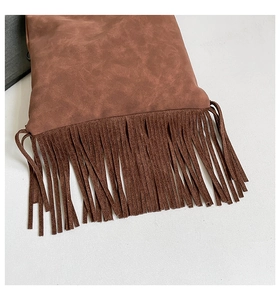 Detailed view of the dark brown suede fabric and long decorative fringe on this bag