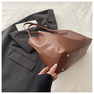 Detail view of brown leather tote bag with silver protective studs and quality stitching
