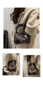 Detail view of deep brown dumpling bag featuring pleated handles and gold chain strap