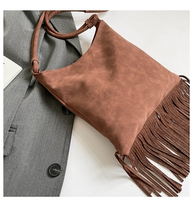 Detailed view of caramel suede shoulder bag featuring long fringe and matte texture