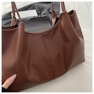 Close-up of deep brown leather tote bag with vertical double stitching detail on fabric