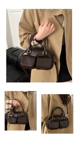 Detail of dark brown leather boston bag with dual front pockets and adjustable strap