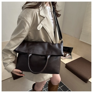 Detailed view of dark brown pebbled leather texture on a vintage tote bag with shoulder strap