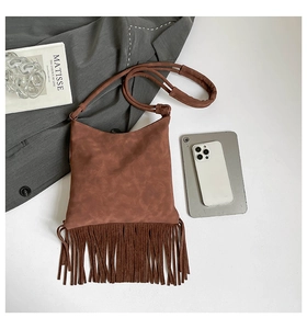 Détail d'un sac bandoulière en daim marron foncé avec longues franges et bandoulière