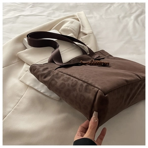 Detail of dark brown tote bag featuring leopard print panel and woven strap