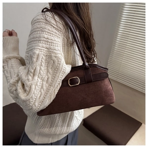 Detail of dark brown suede shoulder bag with leather strap and gold buckle accent