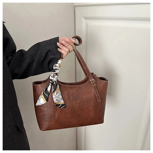 Détail d'un sac cabas en cuir marron avec foulard en soie et boucle métallique