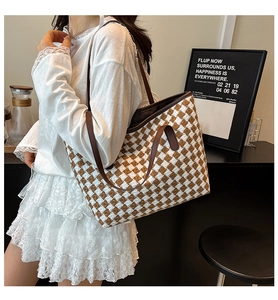 Close-up of woven checkered tote bag with brown leather handles in a lifestyle setting