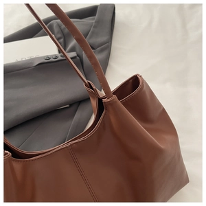 Detail of deep brown leather tote bag with fine stitching and slim dual shoulder straps