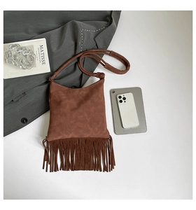 Detail of dark brown suede crossbody bag featuring long fringe and thin shoulder strap