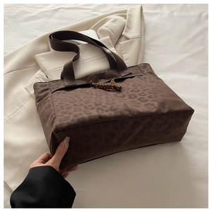 Close-up of leopard print tote bag with woven rope detail and side pocket on blazer