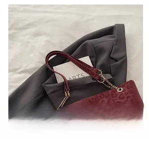 Dettaglio della borsa tote leopardata bordeaux con chiusura dorata e tracolla in catena