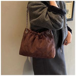 Nahaufnahme der gesteppten dunkelbraunen Wildledertasche mit Goldkette im Retro-Stil