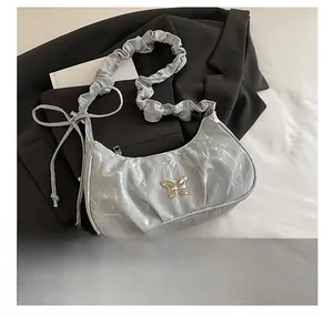 Detail of silver pleated bag featuring metal butterfly buckle and ruched strap